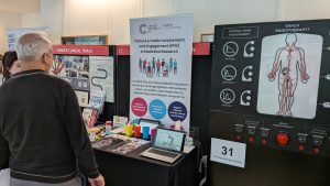 RadNet stand at the UCLH Research Open Day. Image shows researcher speaking with a visitor in front of the stand.
