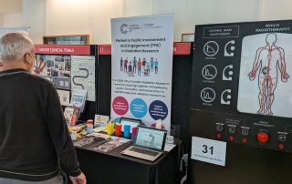 RadNet stand at the UCLH Research Open Day. Image shows researcher speaking with a visitor in front of the stand.
